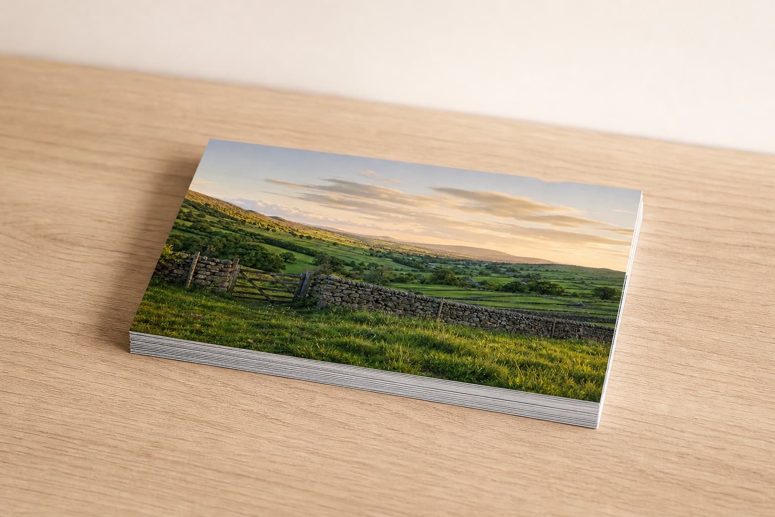 A shallow stack of 12x8" photo prints on a pale photo-lab worktable